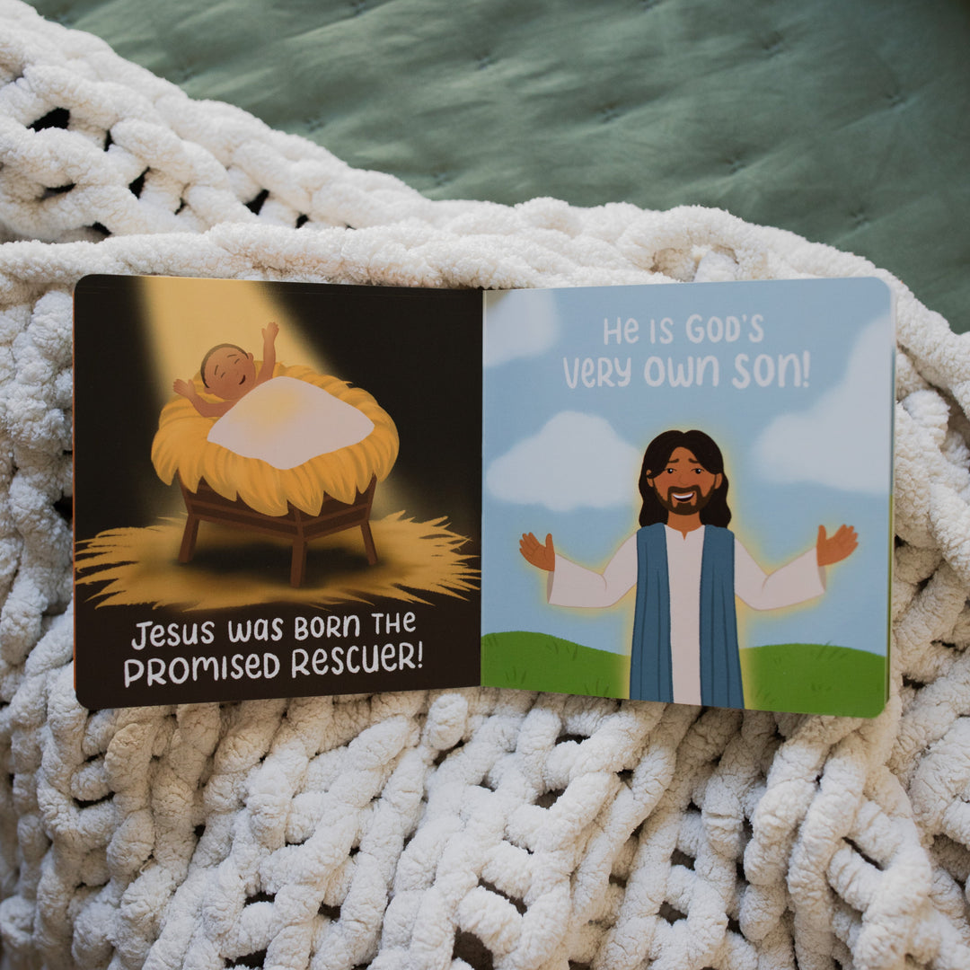 The Story of the Bible The Rescuer Arrives Book opened to Jesus' birth page on a white knitted blanket on a green blanket