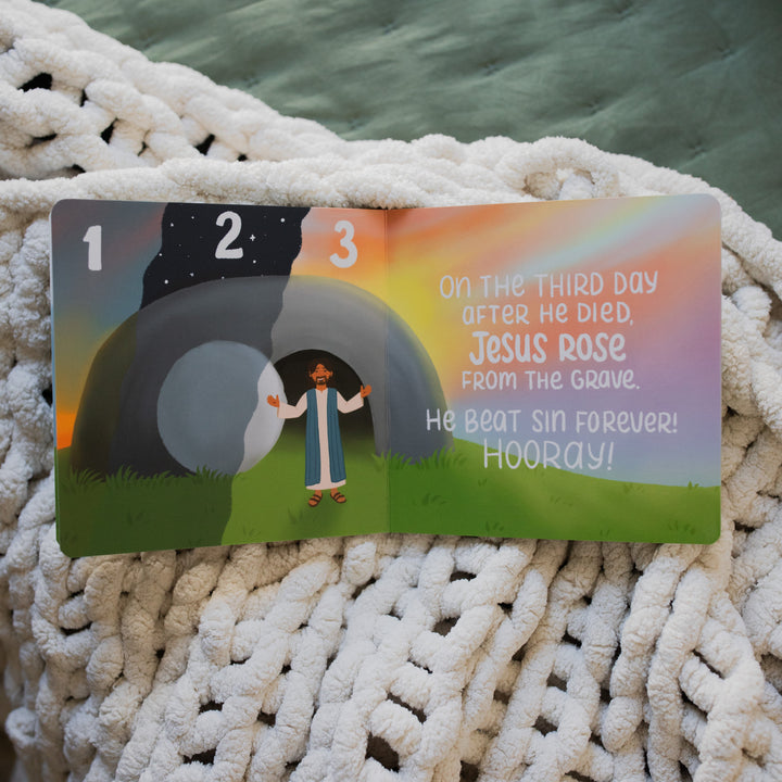 The Story of the Bible The Rescuer Arrives Book Opened to Jesus' resurrection on a white knitted blanket on a green blanket