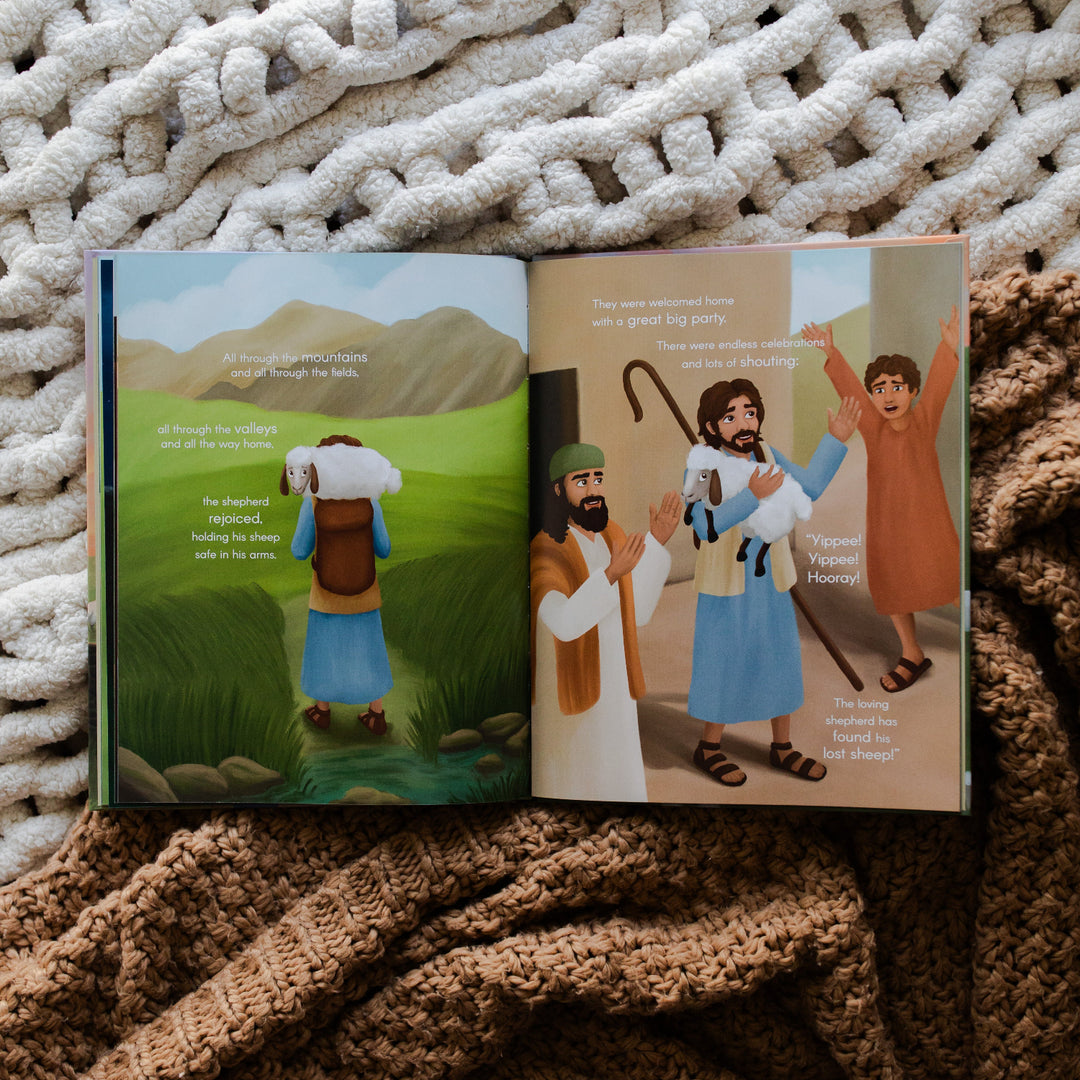 The Story of the Lost Sheep Book page of a man carrying a baby sheep on his back and the other page has 3 men celebrating while one holds a baby sheep; the book is two blankets, one cream colored blanket and one brown