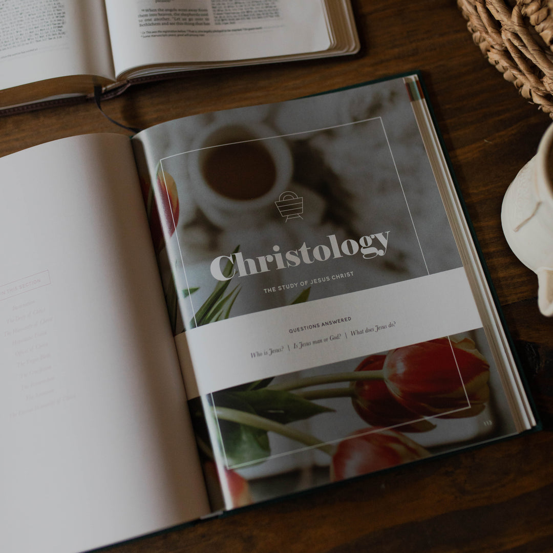 Book titled 'Christology' on a wooden surface with another book open in the background.