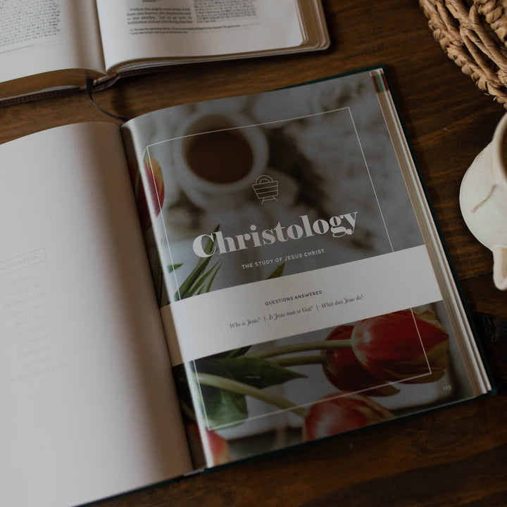 Book titled 'Christology' on a wooden surface with another book open in the background.