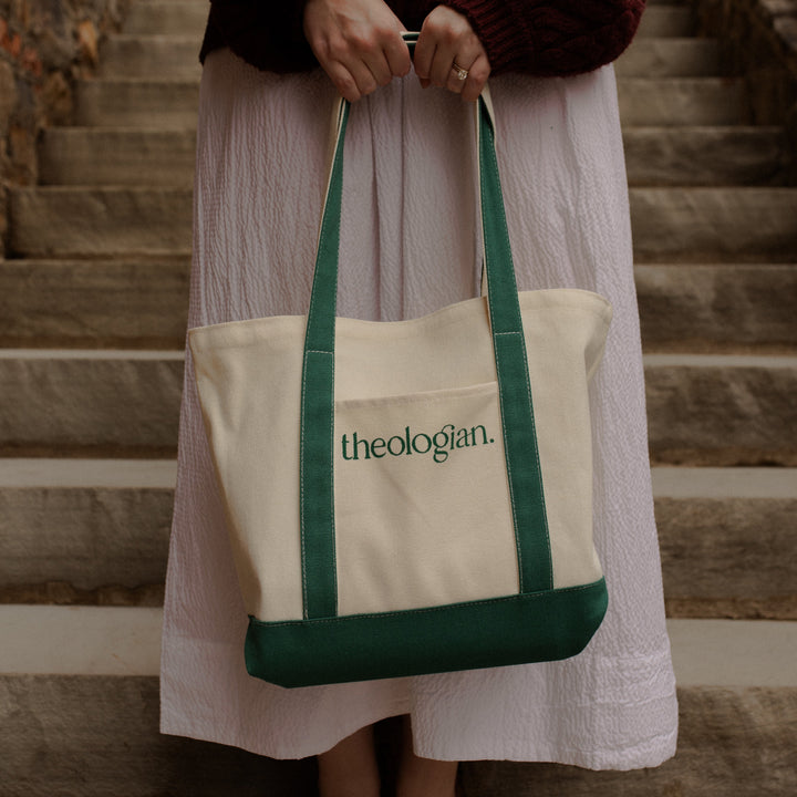 A woman on a set of stairs holding a bag that says theologian on it
