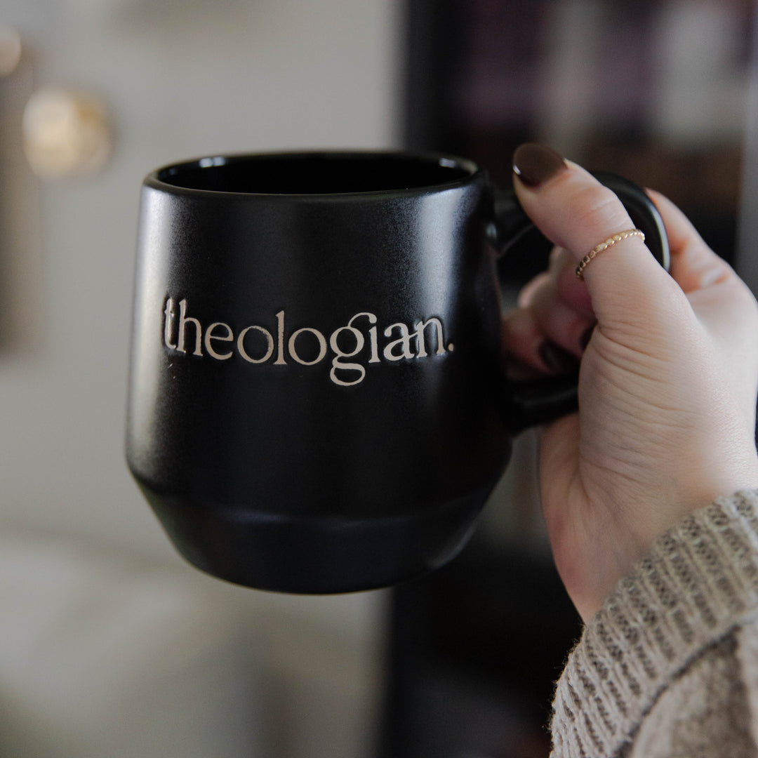 black christian mug that says theologian on it and woman holding it 