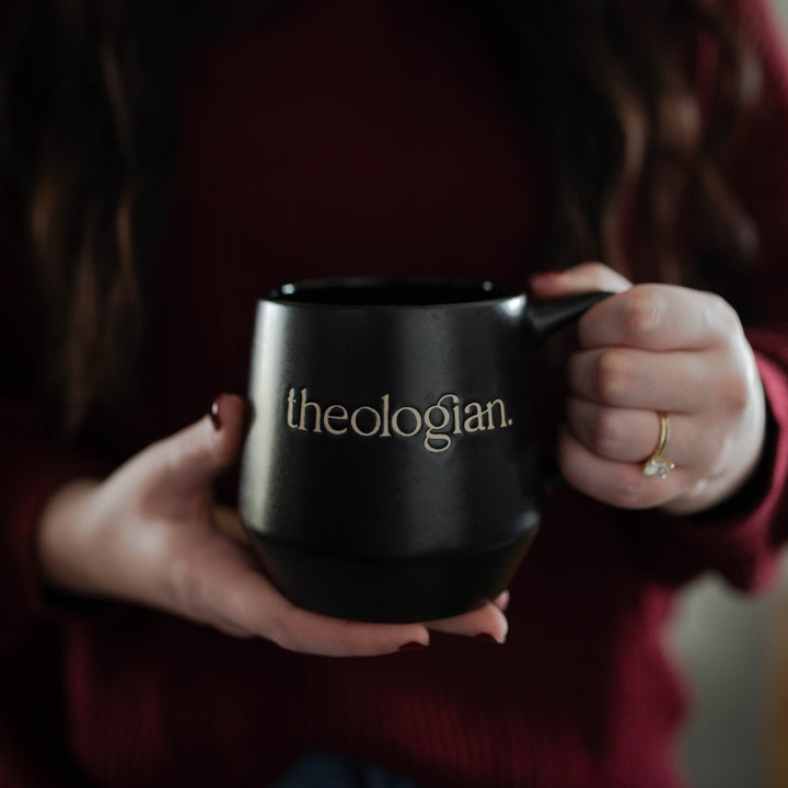 Black ceramic Theologian mug for Christians and a woman holding it