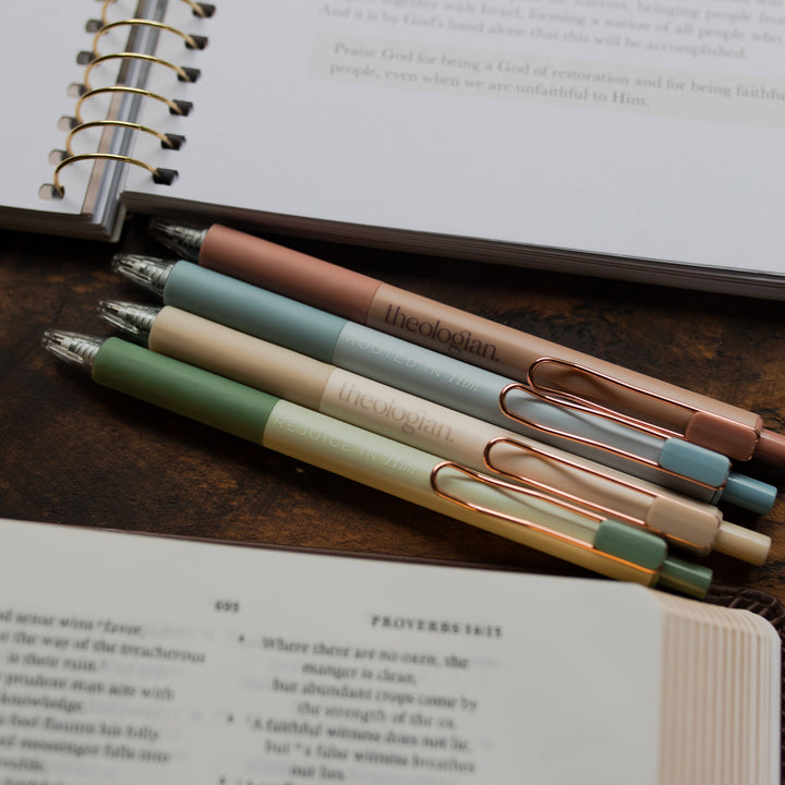 4 Theologian Pens laying above an open bible and an open journal