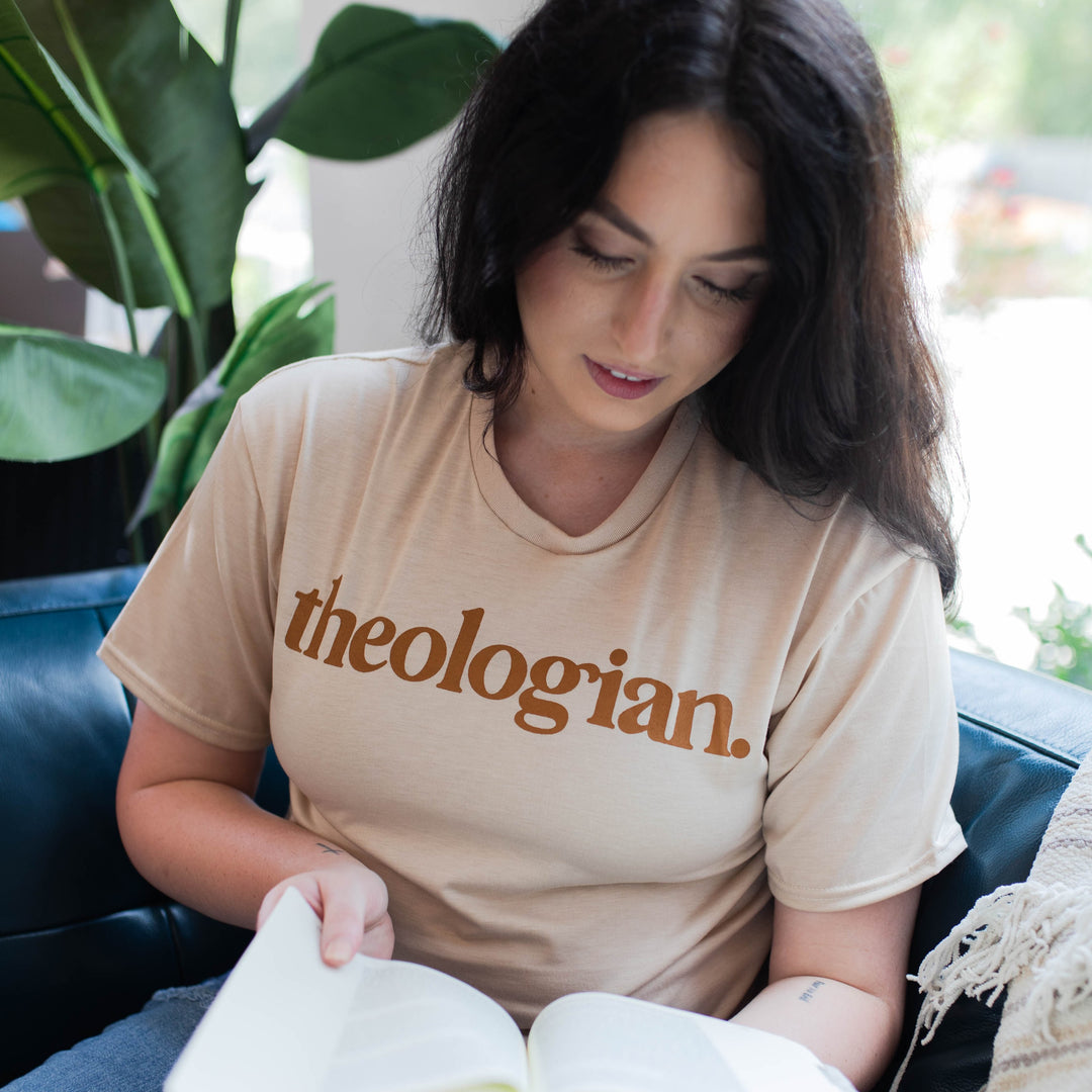 woman wearing theologian tee shirt reading a Bible