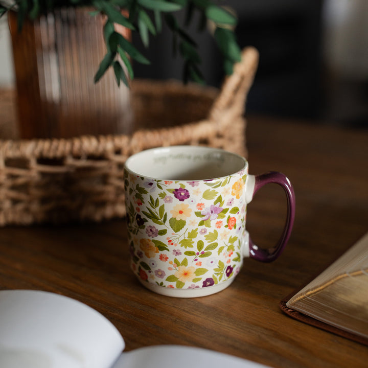 Today Matters Magnolia Floral Mug on a brown wooden table next to a brown woven basket, and open Bible and an open book