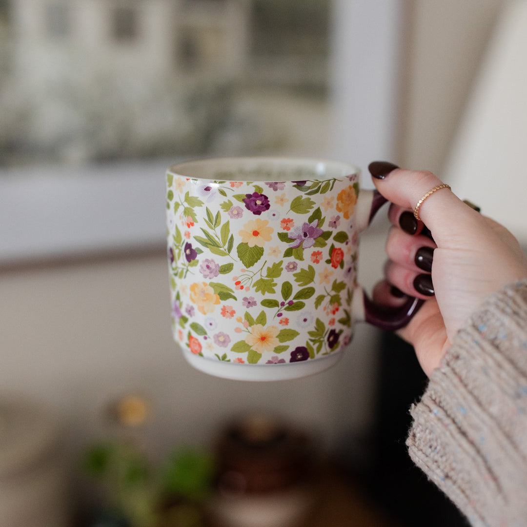 A woman holding the Today Matters Magnolia Floral Mug in her right hand