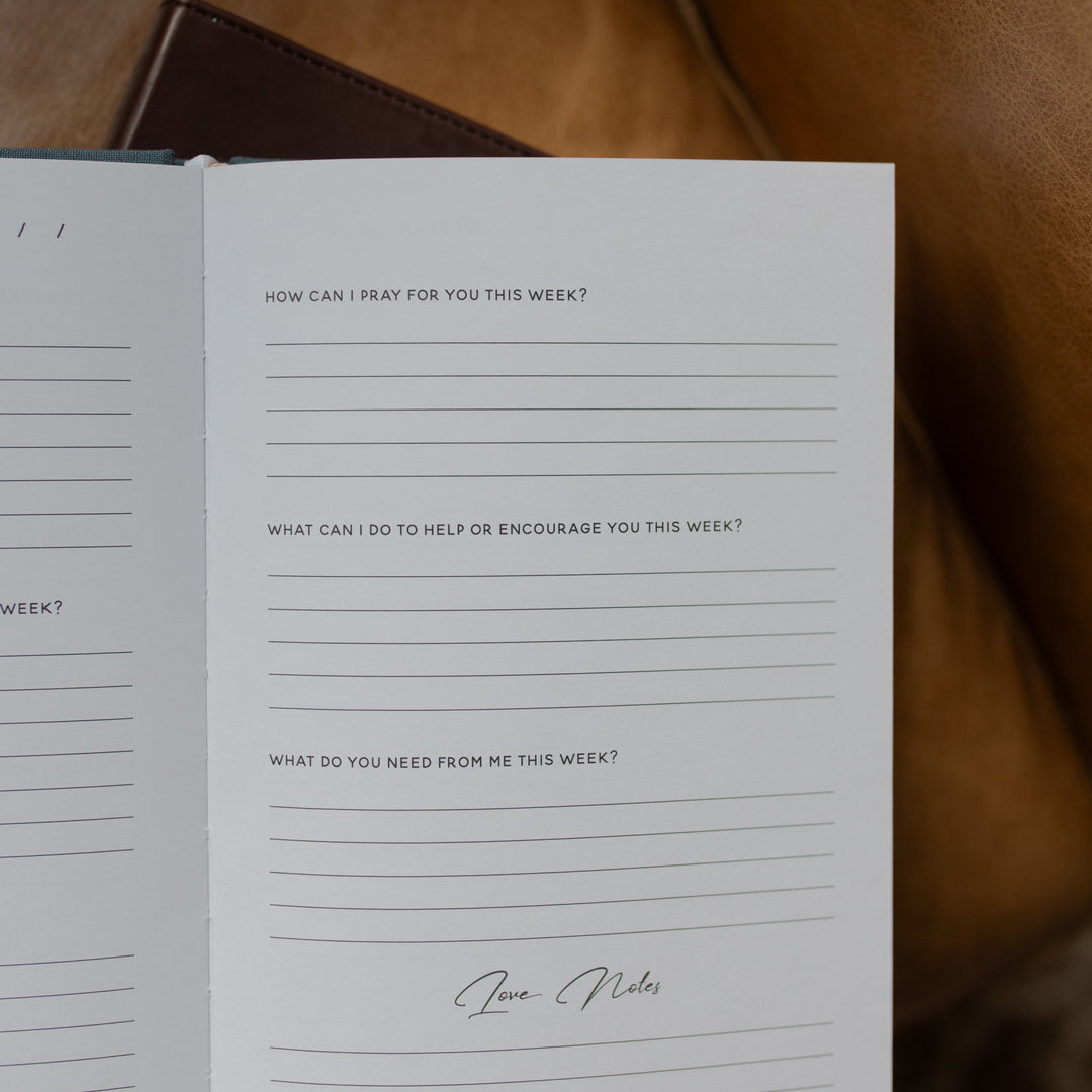 Open book with prayer journal prompts on a brown leather surface