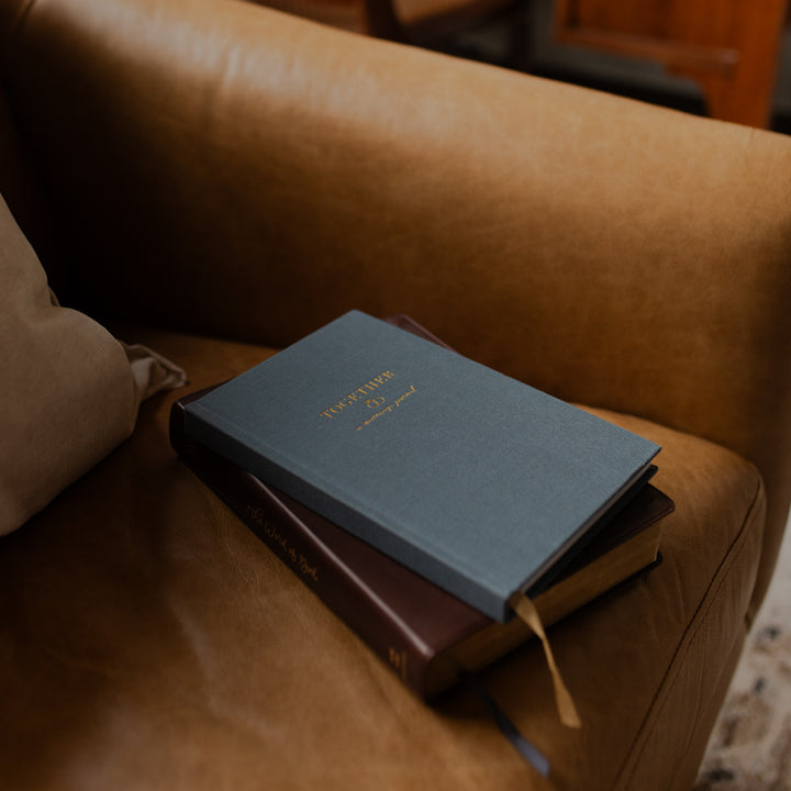 Two books stacked on a brown leather couch