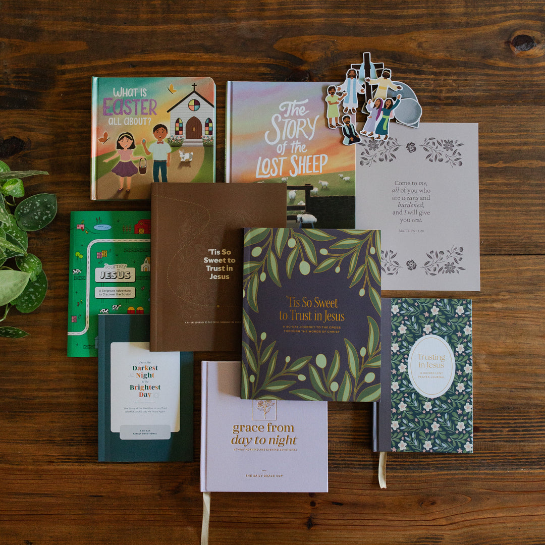 The Ultimate Lent Bundle laying on a brown wooden table next to some greenery