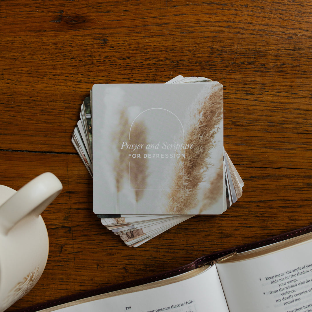 A stack of the Verse Cards for Depression on a wooden table next to a coffee cup