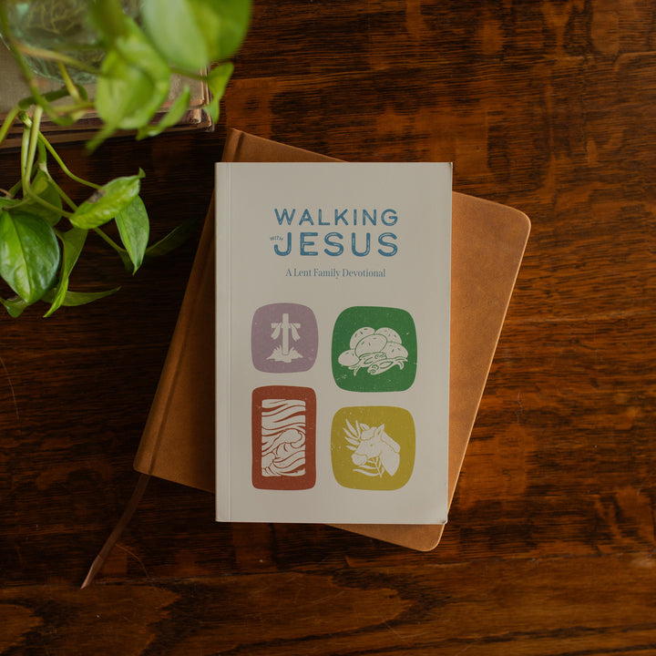 Walking with Jesus Study Cover on a journal on a wooden table near some greenery