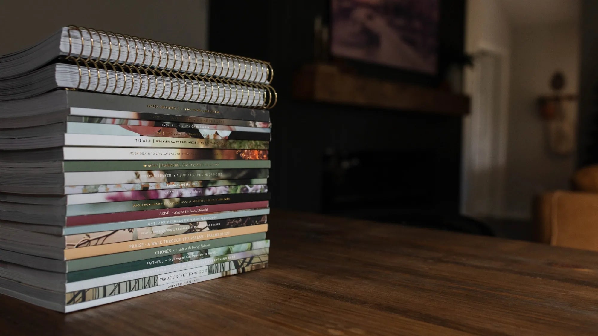 A stack of books neatly arranged on a wooden table, showcasing various colors and sizes.