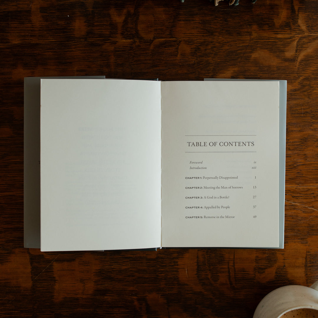 What did you expect book opened to the Table of Contents on a wooden table near a coffee cup