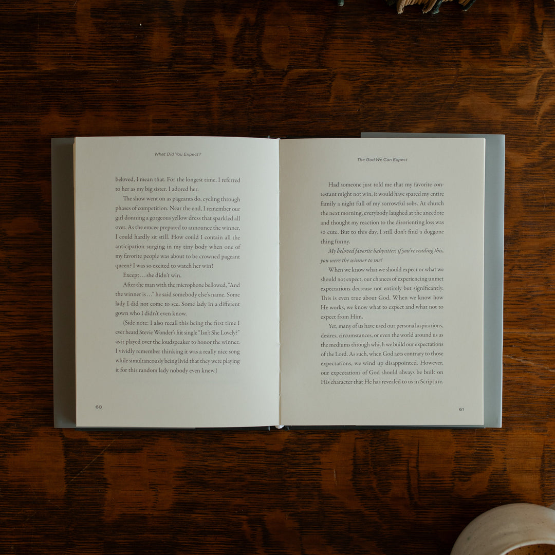 What did you expect book opened to page 60 on a wooden table near a coffee cup