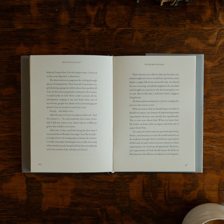 What did you expect book opened to page 60 on a wooden table near a coffee cup