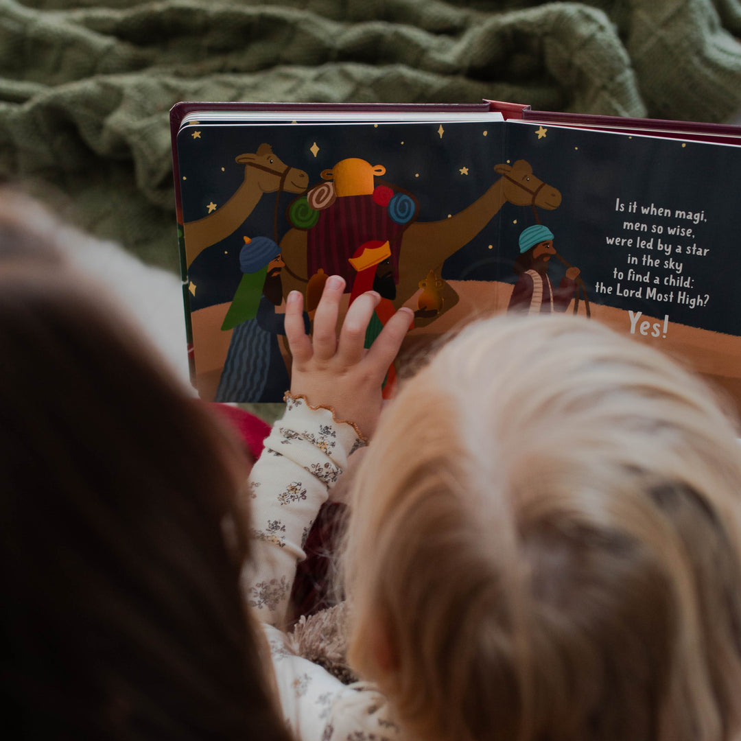 Little girl touching pages in Christian Christmas board book