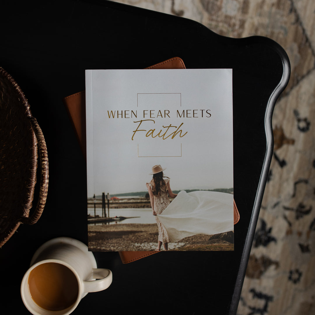 Book titled 'When Fear Meets Faith' on a dark surface with a cup of coffee.