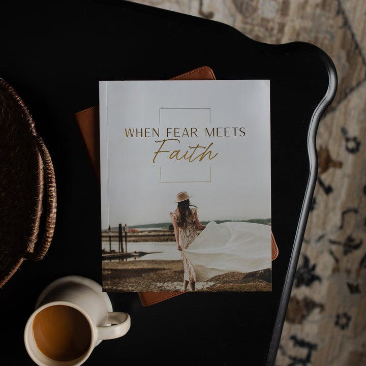 Book titled 'When Fear Meets Faith' on a dark surface with a cup of coffee.