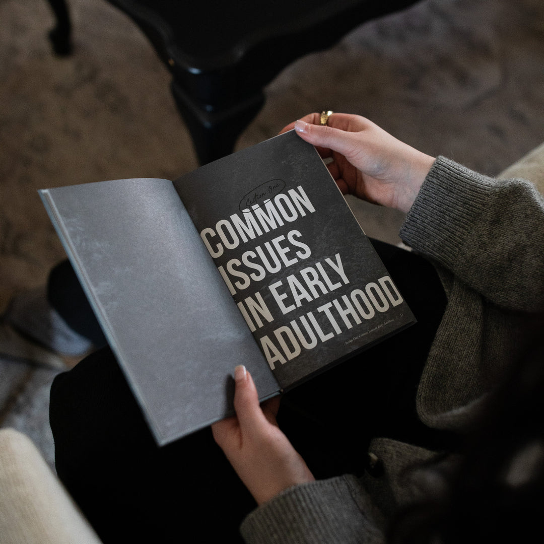 A woman's hands holding open the Where Do I go from Here study on the Section One page next to a black table.