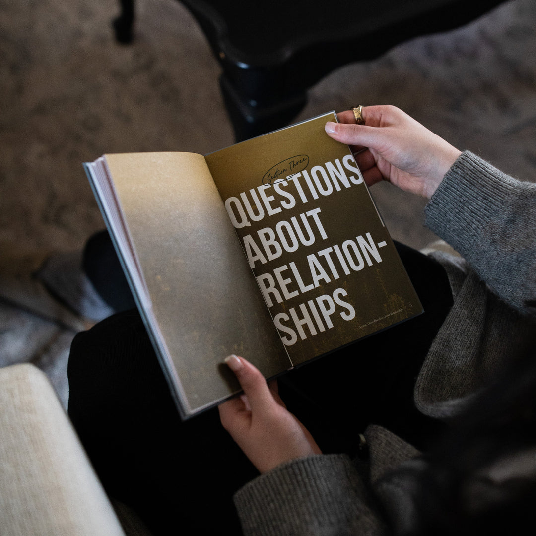 A woman's hands holding open the Where Do I go from Here study on the Section Three page next to a black table.