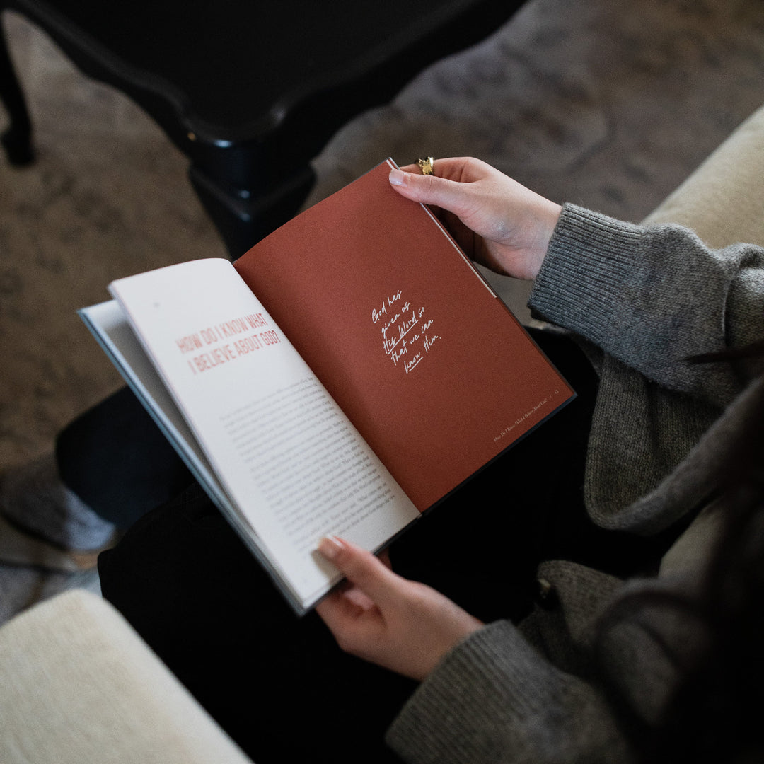 A woman's hands holding open the Where Do I go from Here study on a devotional page next to a black table.