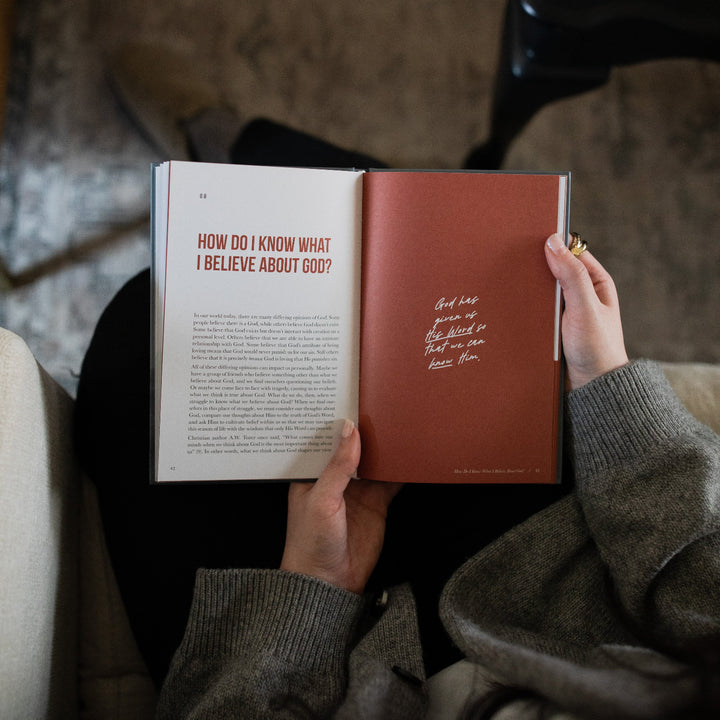 A woman's hands holding open the Where Do I go from Here study on a Devotional page over a gray rug.