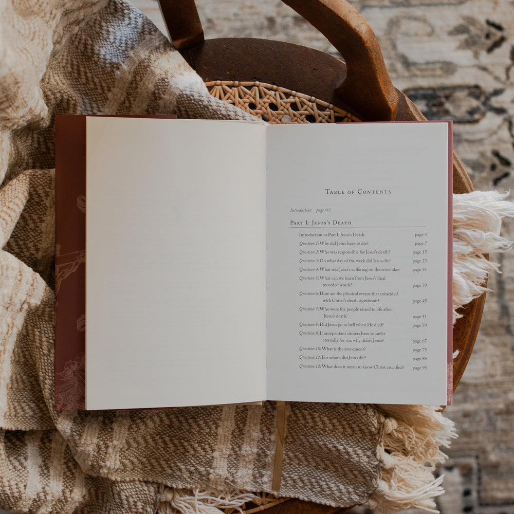 Why Did Jesus Have To Die opened to the table of contents page on a blanket and a woven chair