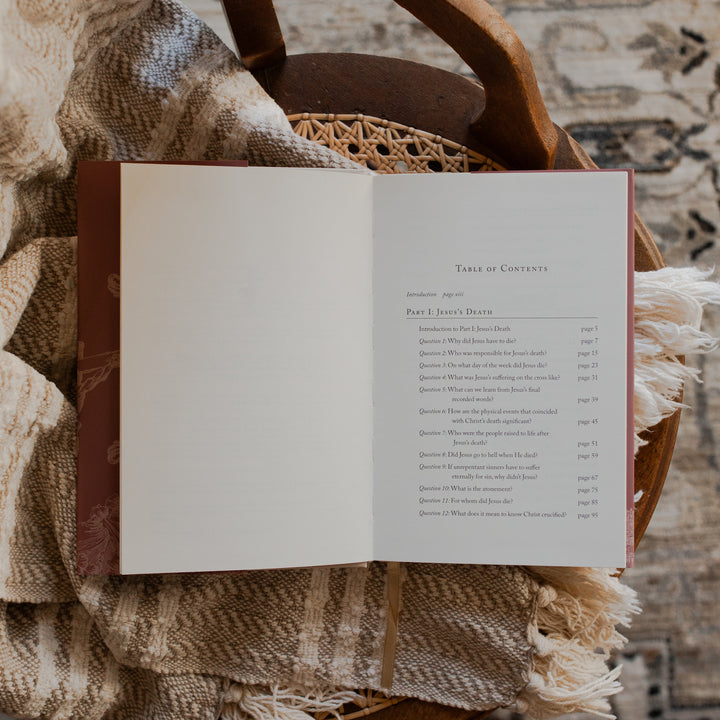 Why Did Jesus Have To Die opened to the table of contents page on a blanket and a woven chair