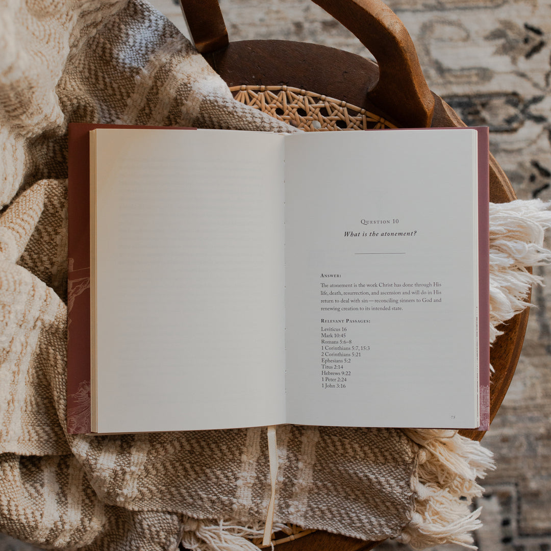 Why Did Jesus Have To Die opened to the the questions 10 page on a blanket and a woven chair