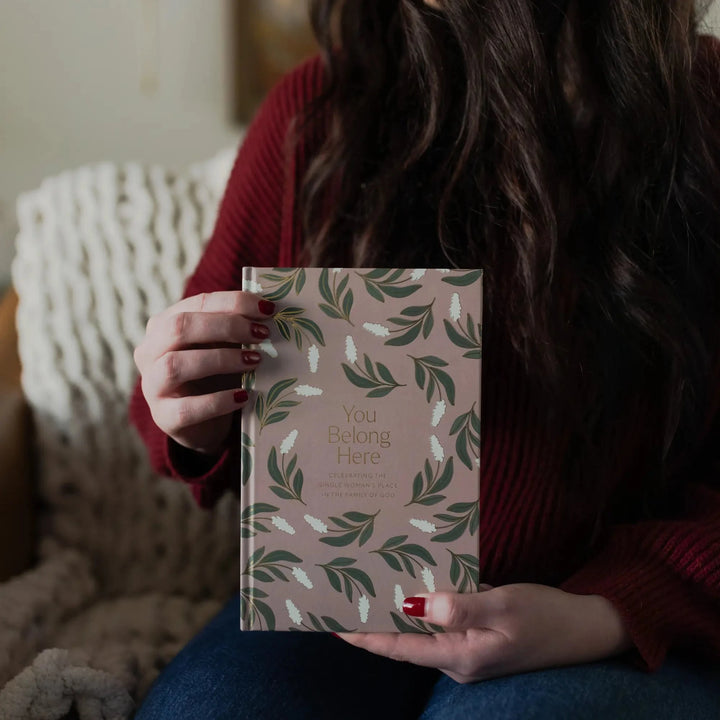 A woman holding a You Belong Here Study upright