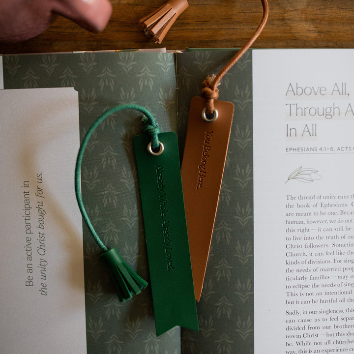 A Brown and a Green You Belong Here Leatherette Bookmarks laying on an open book sitting on a table