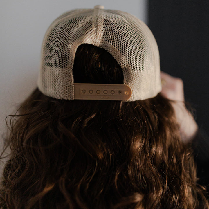 The back of a Woman wearing a You Belong Here Trucker Hat