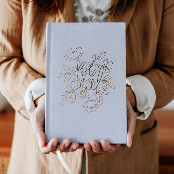 Woman holding Be Still Bible study journal