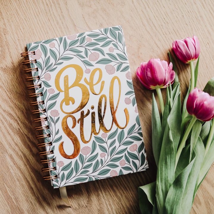 Be Still Bible study journal on table with tulips