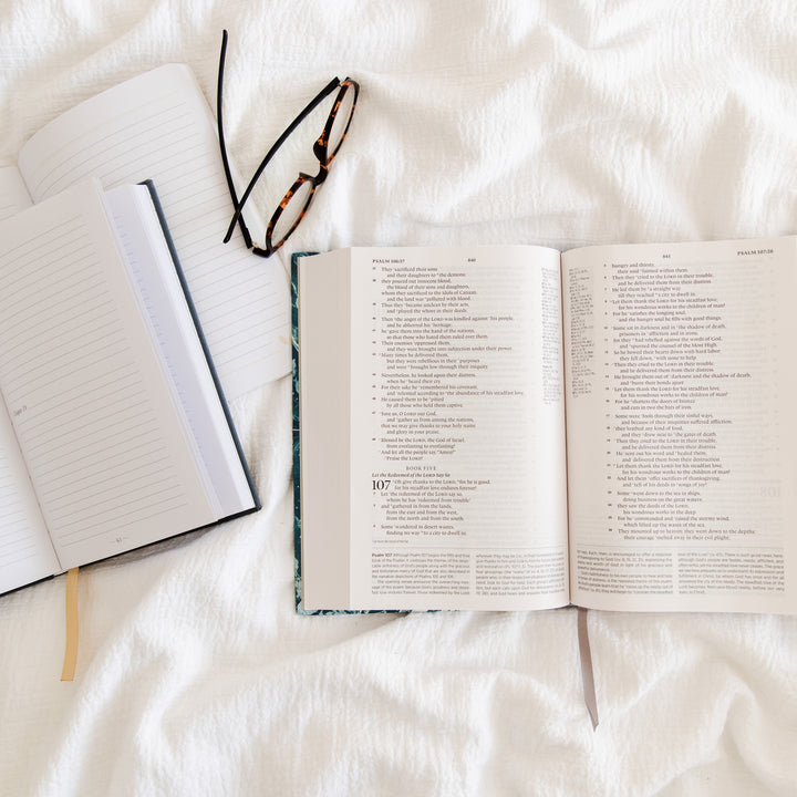 open bible journal and glasses on bed