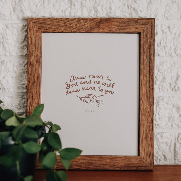 Art print of James 4:8 in a wooden picture frame. The art print is in cursive and has a flower under the verse.