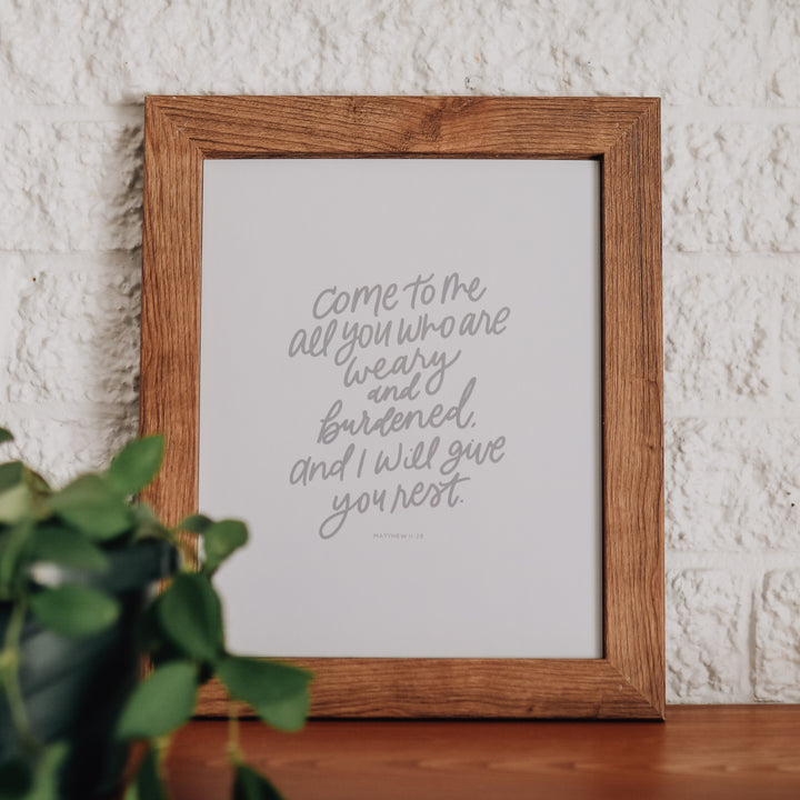 Frame print of Matthew 11:28. The lettering is in gray script and the frame is brown. 