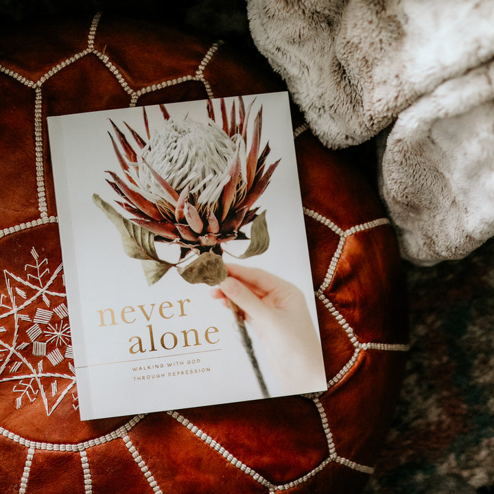 Image of the Never Alone Bible study on a red, leather poof with a faux fur blanket.