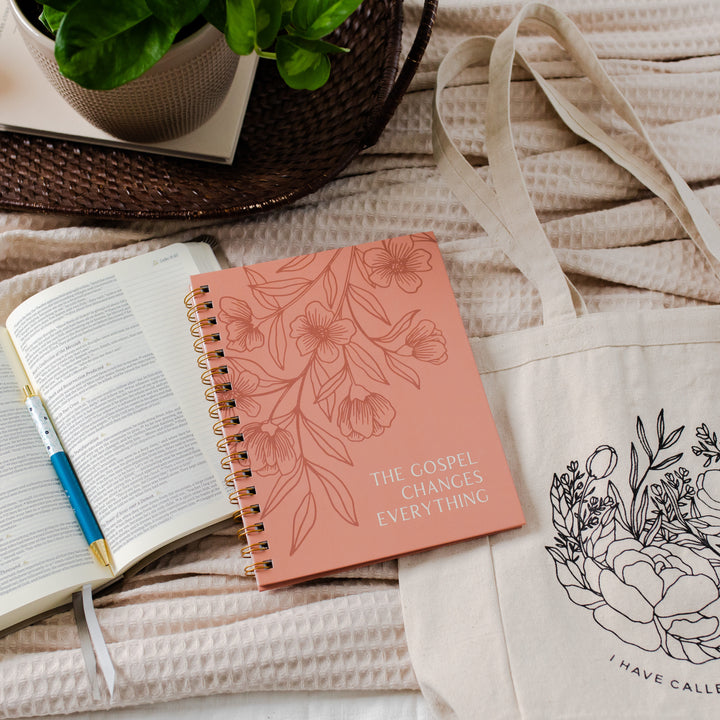 Image of a pink journal on top of a Bible and tote. 