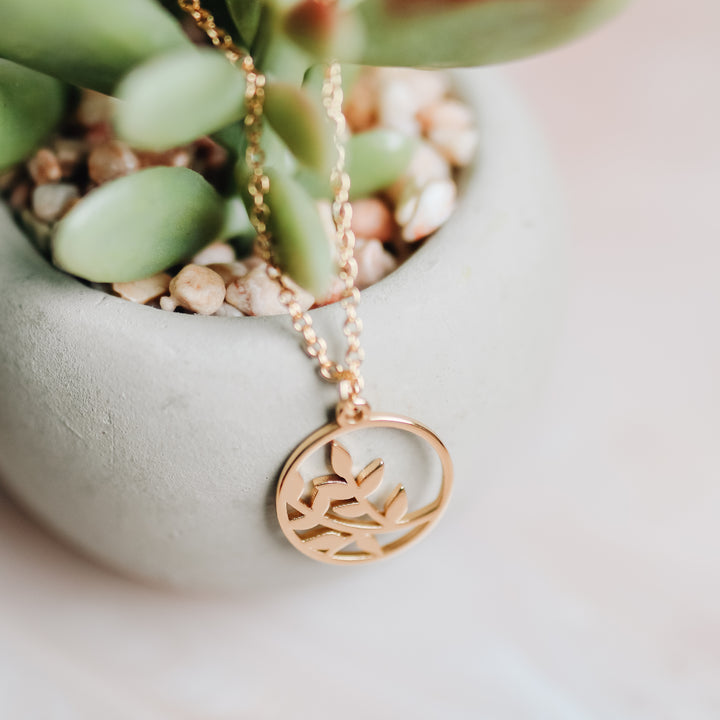 A gold necklace with a branch on it