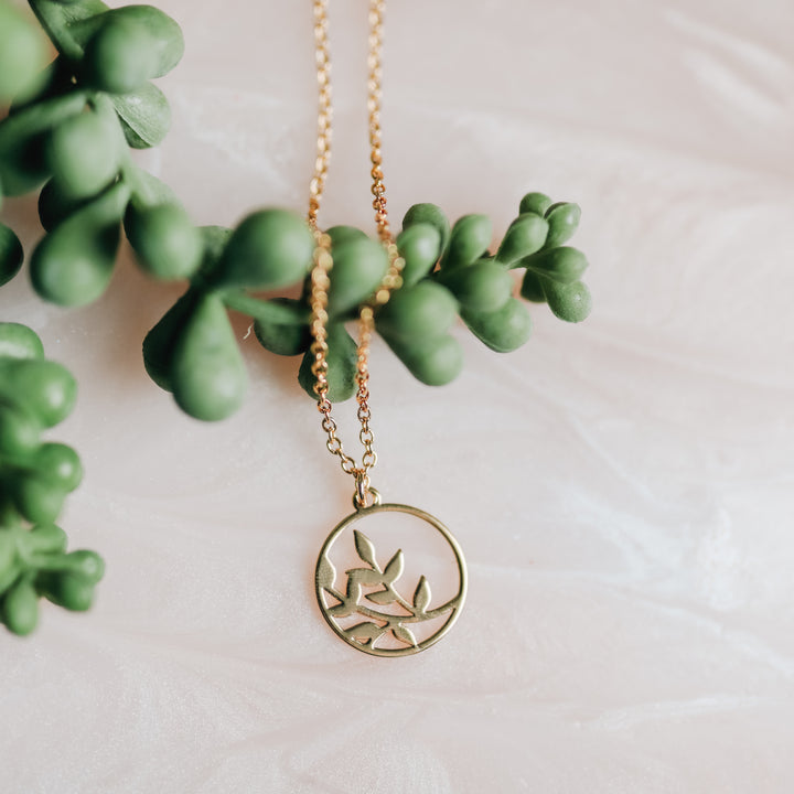 A gold necklace with a branch on it