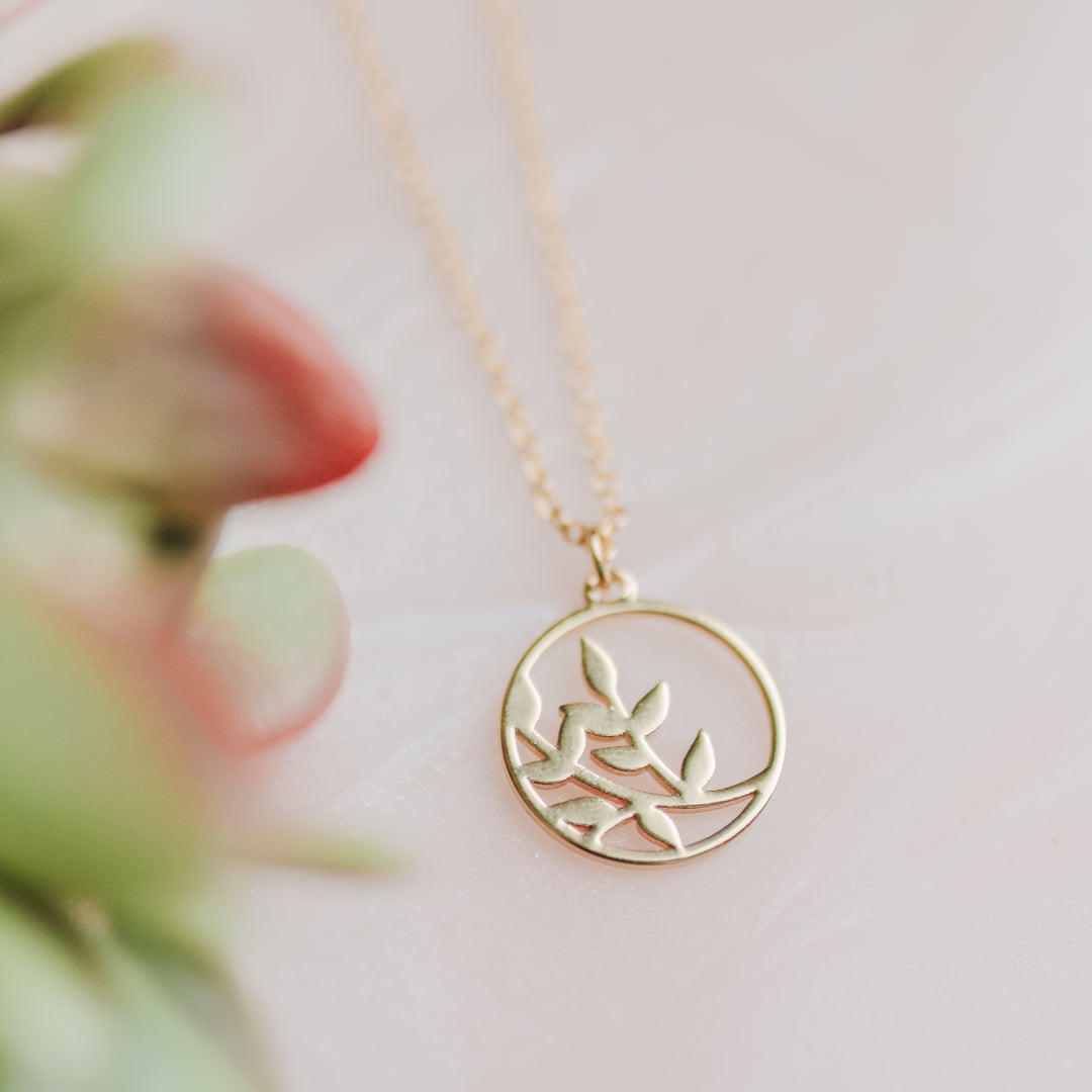 A gold necklace with a branch on it