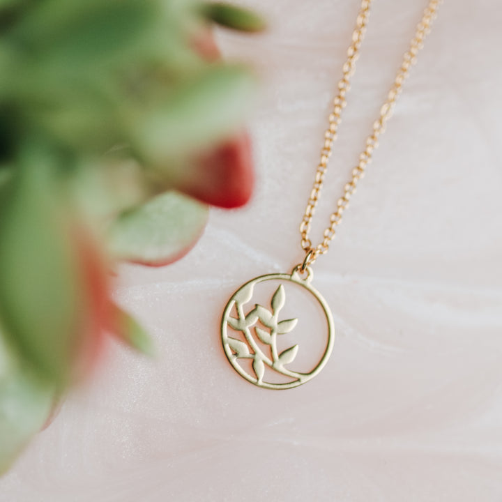 A gold necklace with a branch on it