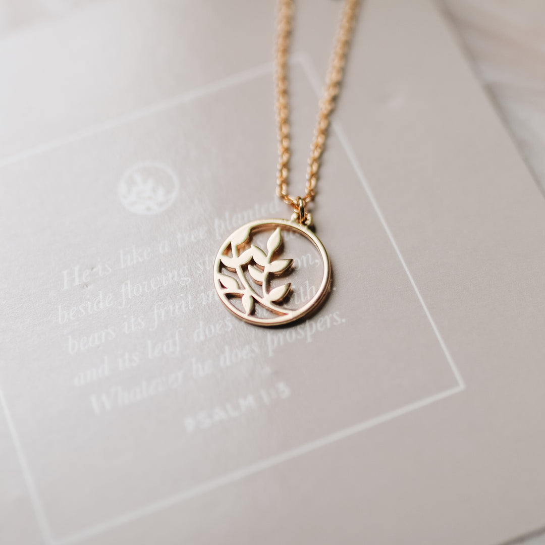 A gold necklace with a branch on it