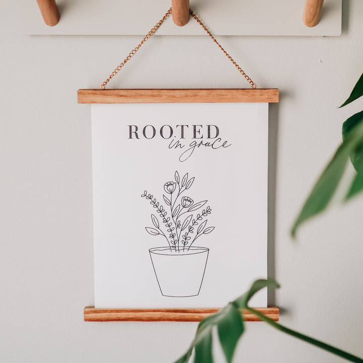 Rooted in Grace print out hanging from wooden pegs on a white wall.