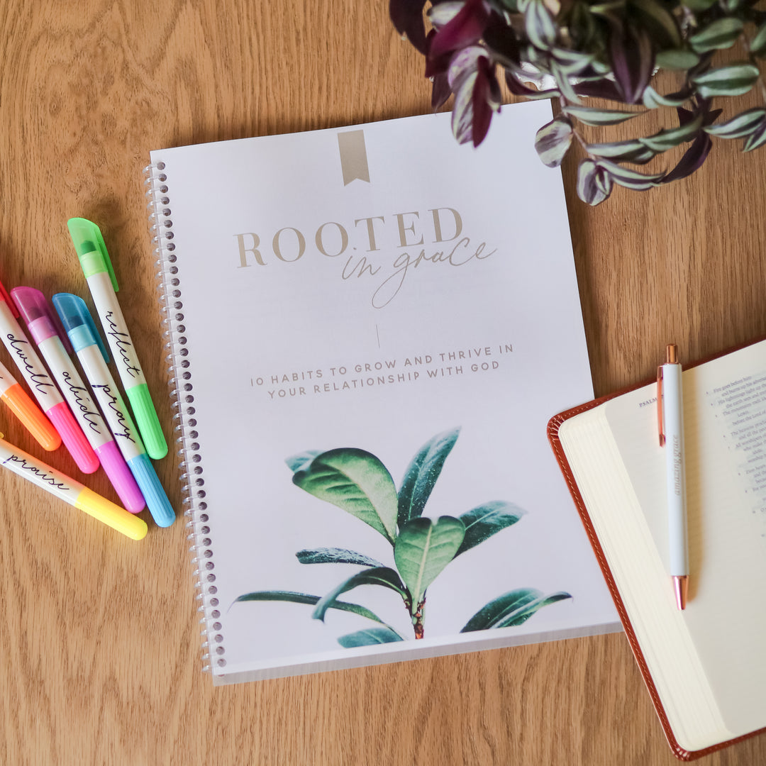 Rooted in Grace workbook next to highlighters on a wooden table. 