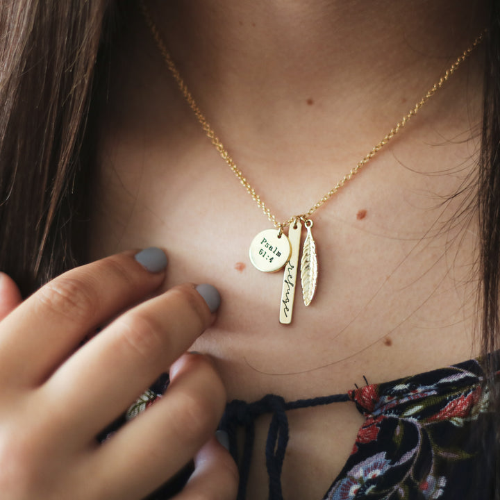 A stack of three gold charms on necklace chain