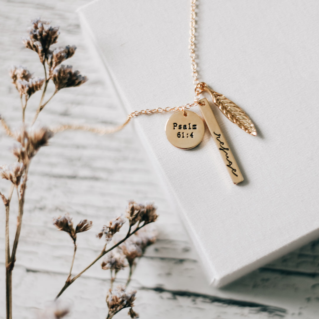 A stack of three gold charms on necklace chain